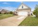 View of the home's driveway, 2-car garage, and brick facade, with well-kept lawn and garden at 7236 Sunset Point Dr, Indianapolis, IN 46259