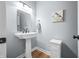 Bright powder room with a pedestal sink, framed mirror, stylish light fixture, and neutral paint at 7236 Sunset Point Dr, Indianapolis, IN 46259