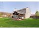Large backyard with green grass, covered patio, and a hot tub at 9011 Harrison Run Dr, Indianapolis, IN 46256