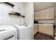 Functional laundry room with shelving, white subway tile, and updated washer and dryer at 9011 Harrison Run Dr, Indianapolis, IN 46256