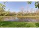A serene pond reflecting the surrounding trees and blue sky, adding natural beauty to the property at 9011 Harrison Run Dr, Indianapolis, IN 46256