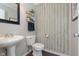 Charming powder room with pedestal sink, decorative shelves, and patterned accent wall at 9011 Harrison Run Dr, Indianapolis, IN 46256