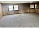 Spacious carpeted den featuring wood paneled walls and natural light from two windows at 10131 Nassau Ln, Indianapolis, IN 46229