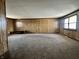 Large den featuring wood paneled walls, carpeted floors and natural light from a large window at 10131 Nassau Ln, Indianapolis, IN 46229