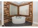 Modern soaking tub surrounded by stone flooring and rustic wood accents in a well-lit bathroom at 10415 Charter Oaks, Carmel, IN 46032