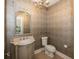 Sophisticated powder room with elegant wallpaper, a decorative mirror, and designer fixtures at 10415 Charter Oaks, Carmel, IN 46032