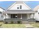 Charming home featuring stone accents, gray siding, a welcoming front porch, and architectural roof at 1056 N Mount St, Indianapolis, IN 46222