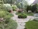 Backyard featuring professional landscaping with mature trees, flowers, shrubs, and stone walkway at 10614 Winterwood, Carmel, IN 46032