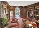Elegant library with floor to ceiling custom wood bookshelves, a cozy sitting area, and doorway with backyard view at 10614 Winterwood, Carmel, IN 46032