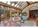 Sunroom features stone wall, glass ceiling, dining table, chandelier, and view into a wood-paneled library at 10614 Winterwood, Carmel, IN 46032