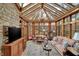 Beautiful sunroom features a stone accent wall, vaulted glass ceilings, and elegant furnishings at 10614 Winterwood, Carmel, IN 46032