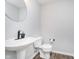 Stylish powder room featuring modern fixtures, pedestal sink, round mirror, and wood-look floors at 10628 Mangrove Dr, Indianapolis, IN 46239