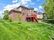 Brick home's backyard with lush lawn, a red deck and staircase, perfect for outdoor enjoyment at 10792 Harbor Bay Dr, Fishers, IN 46040