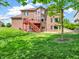 Expansive backyard showcasing a brick house with a red deck and staircase, ideal for entertaining at 10792 Harbor Bay Dr, Fishers, IN 46040