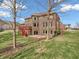 Expansive backyard view featuring a two-story brick home, complemented by a red deck and lush lawn at 10792 Harbor Bay Dr, Fishers, IN 46040