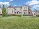 A luxury two-story home with a turret, stone accents and well-maintained landscaping on a green lawn at 10792 Harbor Bay Dr, Fishers, IN 46040