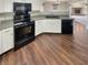 The kitchen features black appliances, bright white cabinets, and wood-look flooring at 12416 Teacup Way, Indianapolis, IN 46235