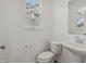 Classic powder room featuring a pedestal sink, toilet, and a window for natural light, set against neutral walls at 15982 Meadow Frost Ct, Fishers, IN 46037