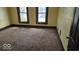 Bedroom featuring worn carpet, painted walls, and dark trim around two large windows at 18 N Sherman Dr, Indianapolis, IN 46201