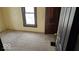 Bedroom featuring tan walls, gray carpet, a window, and a dark-stained door at 18 N Sherman Dr, Indianapolis, IN 46201