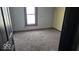 Bedroom with neutral carpet, a window with dark trim and door leading out of the space at 18 N Sherman Dr, Indianapolis, IN 46201