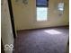 A bedroom with tan walls, a window and an unadorned mirror featuring wall scribbles and brown carpet at 18 N Sherman Dr, Indianapolis, IN 46201