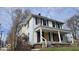 Two-story home with a covered porch, boarded windows, and some deferred maintenance at 18 N Sherman Dr, Indianapolis, IN 46201