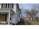 Side view of a two-story home with boarded windows and a covered porch at 18 N Sherman Dr, Indianapolis, IN 46201