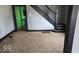Shows a living room with light gray walls, a dark staircase, and carpeted floor at 18 N Sherman Dr, Indianapolis, IN 46201