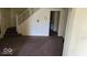 Vacant living room featuring neutral carpeting and staircase access at 18 N Sherman Dr, Indianapolis, IN 46201