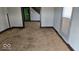 Shows a living room with light gray walls, dark baseboards, and carpeted floor in need of repair at 18 N Sherman Dr, Indianapolis, IN 46201