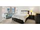 Bedroom with a queen bed, large windows, and a comfortable sitting area with a blue loveseat at 226 N Cleveland St # 226E, Indianapolis, IN 46204
