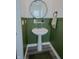 Elegant powder room with green wainscoting, pedestal sink, and a round mirror for a modern touch at 2349 Dixon Creek Dr, Whitestown, IN 46075