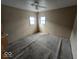 Empty bedroom with neutral carpet and two windows, offering a bright and airy space for remodeling at 2420 N Macedonia Ave, Muncie, IN 47303