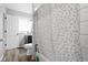 Bright bathroom with a wood-look floor, large window, shower/tub with tile surround, and white door at 4407 Barnor Dr, Indianapolis, IN 46226