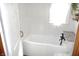 Bright bathroom featuring a clean white bathtub with black faucet and shelving next to the tub at 6041 Dewey Ave, Indianapolis, IN 46219