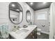Contemporary bathroom featuring double sinks, unique mirrors, modern fixtures, and dark gray tile flooring at 671 Spring Hills Dr, Zionsville, IN 46077