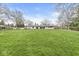 Expansive green lawn with a single story home and a view of mature trees in the background at 671 Spring Hills Dr, Zionsville, IN 46077