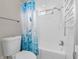 Bathroom featuring a white bathtub with a shower, toilet, and a window at 7540 S Mooresville Rd, Indianapolis, IN 46221