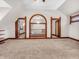 Spacious bonus room features a vaulted ceiling, neutral carpet, and striking wood trim around openings to other rooms at 7540 S Mooresville Rd, Indianapolis, IN 46221