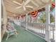 Inviting covered porch with green painted floors, ceiling fans, and patriotic bunting decorations at 7540 S Mooresville Rd, Indianapolis, IN 46221