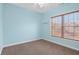 This carpeted bedroom features neutral colors and a window with wooden blinds at 7845 W Hillside Dr, Columbus, IN 47201
