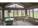 A bright sunroom with multiple windows, table with chairs, and seating area with floral chair at 805 Stewart Rd, Anderson, IN 46012