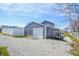 View of the detached garage with a white door and gravel driveway on a sunny day at 97 N Maple St, Pittsboro, IN 46167
