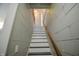 Ascending staircase featuring painted risers and treads, a stained handrail, and finished wall paneling at 97 N Maple St, Pittsboro, IN 46167