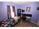 This purple bedroom features hardwood floors, with a bed and a desk with multiple screens at 11403 Fairweather Pl, Indianapolis, IN 46229