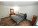 This bedroom features hardwood floors, white walls, a dresser with a mirror, and a bedside table at 11403 Fairweather Pl, Indianapolis, IN 46229