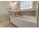 Bright bathroom featuring a white bathtub with tile surround and a window with blinds for natural light at 13875 Ambria Dr, McCordsville, IN 46055