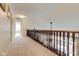 Carpeted upstairs hallway featuring a dark wooden railing and views of the living spaces below at 13875 Ambria Dr, McCordsville, IN 46055