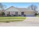 Charming ranch-style home with a brick facade, attached garage, and manicured front lawn on a sunny day at 2231 Reston Ln, Columbus, IN 47203